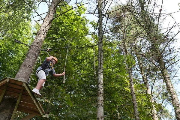 boy climbing and taking on the challenge of a high ropes obstacle challenge course