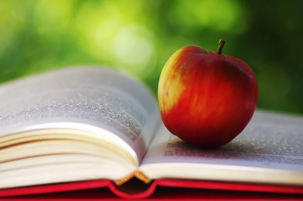 Roter Apfel Mit Aufgeschlagenem Buch Auf Grünem Hintergrund — Stockfoto