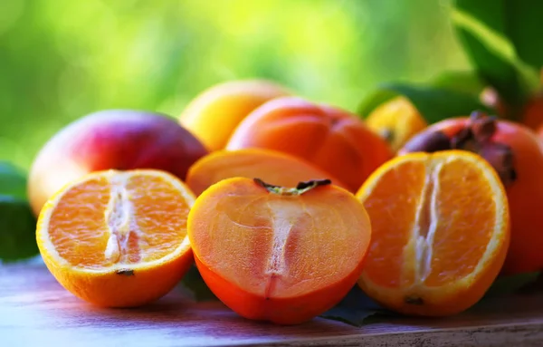 Rijpe Kaki Gesneden Sinaasappelen Groene Achtergrond — Stockfoto