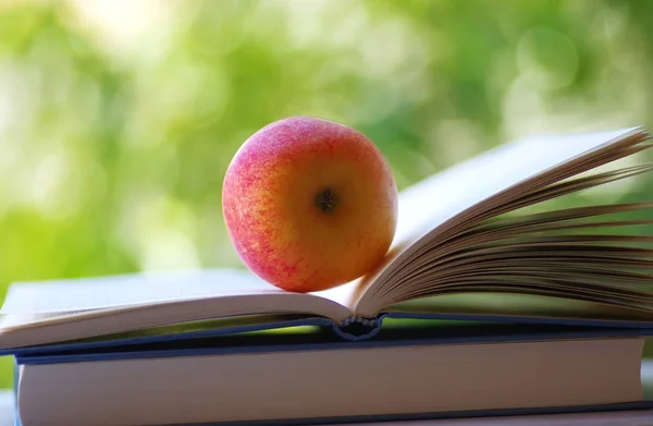Açık bir kitapta kırmızı bir elma — Stok fotoğraf