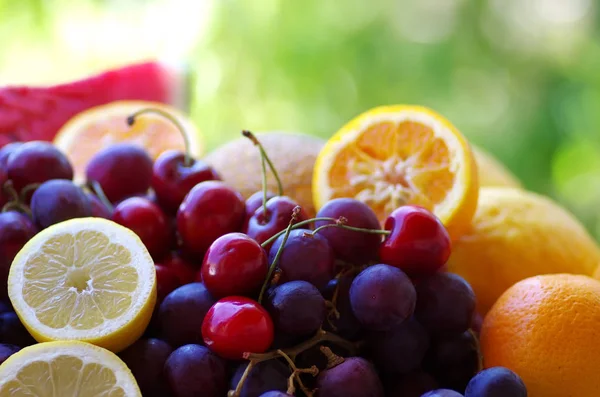 Frutas cítricas, cherrys e uvas na mesa — Fotografia de Stock