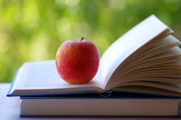 Uma maçã vermelha em um livro aberto — Fotografia de Stock
