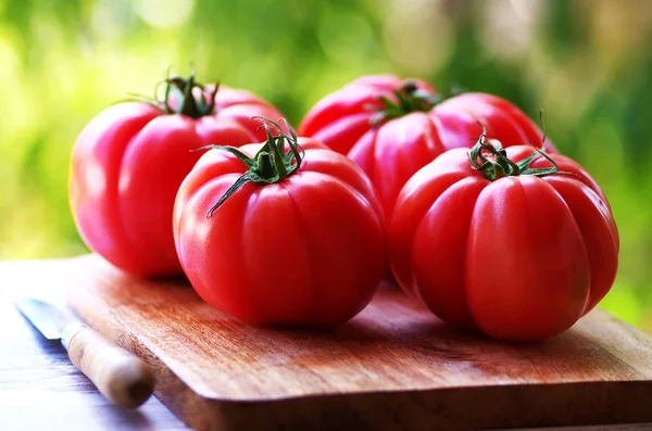 Knife and red tomatoes on wooden table — Stock Photo, Image