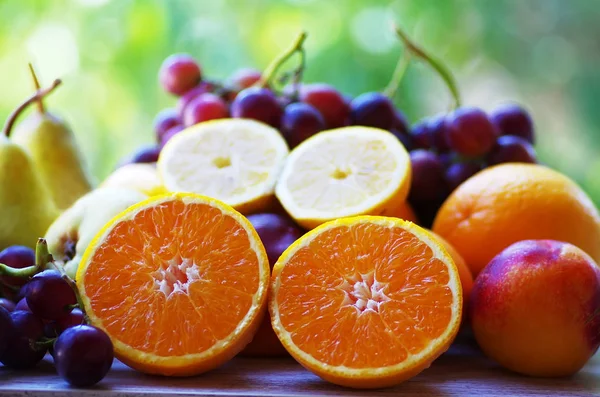 Laranjas, uvas e peras cortadas na mesa — Fotografia de Stock