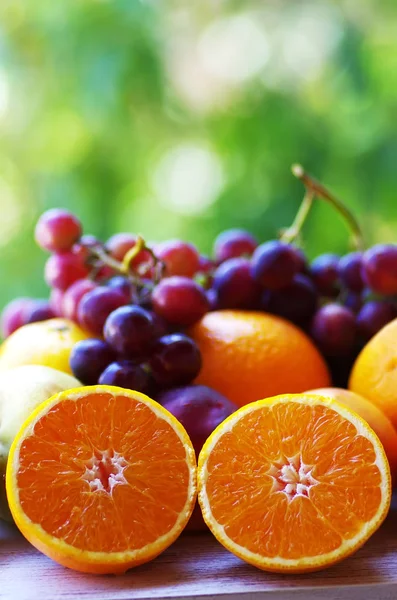 Laranjas e uvas fatiadas, fundo verde — Fotografia de Stock