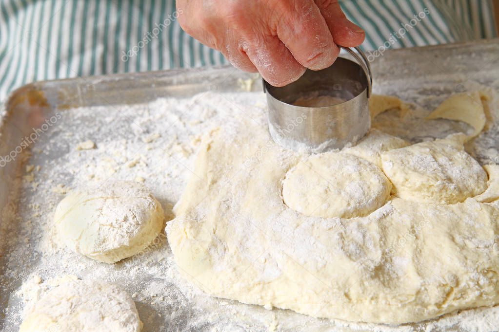 A male cook cuts out biscuits on a floured pan