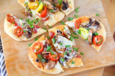 Naan Pizza domates, mantar, pastırma ve scallions porsiyon kesmek