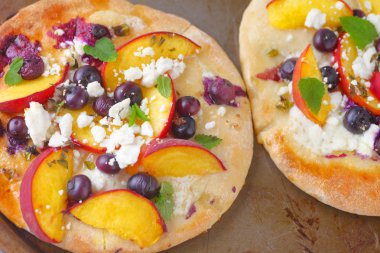 Şeftali dilimleri ve yaban mersini naan ufalanmış beyaz peynir ve nane ile üzerinde