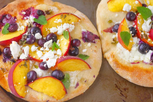 Şeftali dilimleri ve yaban mersini naan ufalanmış beyaz peynir ve nane ile üzerinde