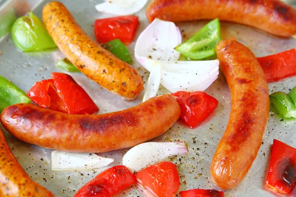 Sheet pan dinner of sausages, green and red bell peppers and onions