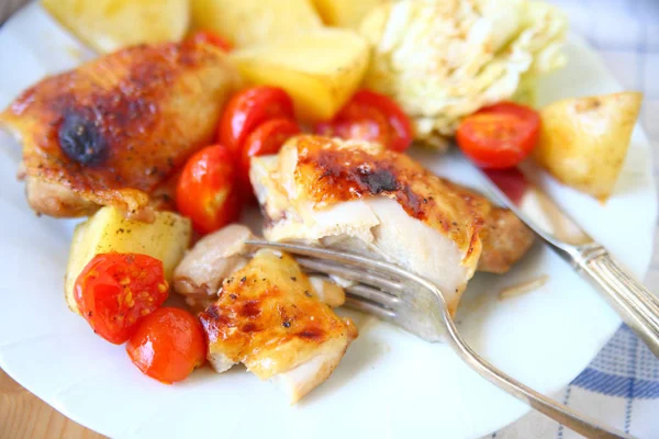 Plate of roast chicken with cherry tomatoes and Yukon gold potatoes