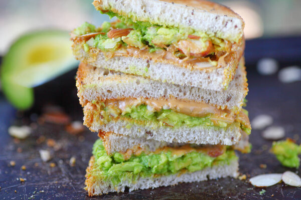 Упакованные трети арахисового масла и сэндвич с авокадо с нарезанным миндалем на ржаном тосте
