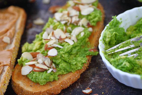 Mashed avocado and sliced almonds on rye bread