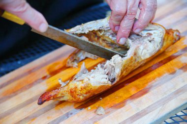 Adamın biri açık havada bir kesme tahtasıyla ördek doğruyor.