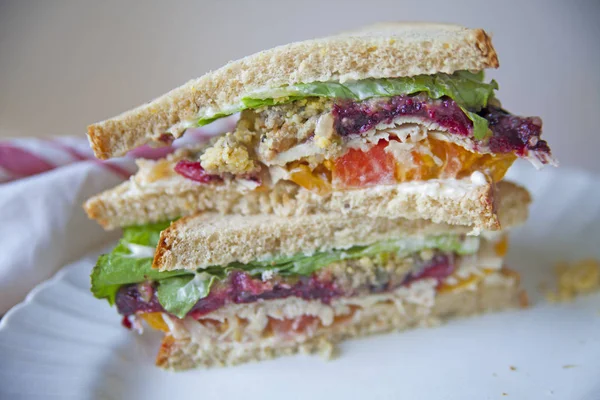 Thanksgiving leftovers sandwich with turkey, cranberry sauce, lettuce, stuffing and tomato