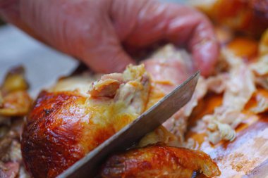 Adam tavuğu kavrayıp, mutfak bıçağıyla parçalara ayırıyor.