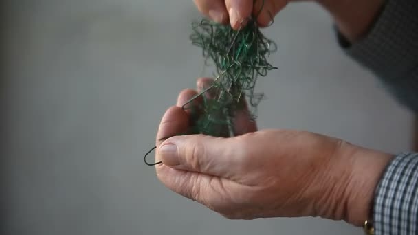 Man Probeert Ontrommelen Een Klomp Van Ornament Hangers — Stockvideo