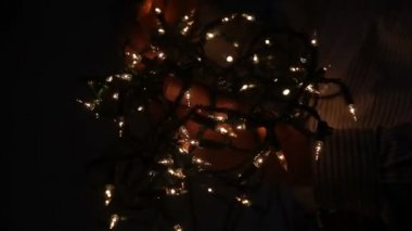 Karanlıkta beyaz Noel ışıklarını çözen adamın profil görünümü