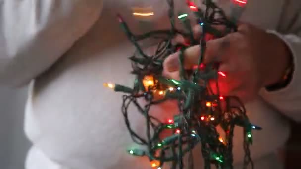 Ein Mann Versucht Eine Kette Von Bunten Weihnachtslichtern Entwirren — Stockvideo