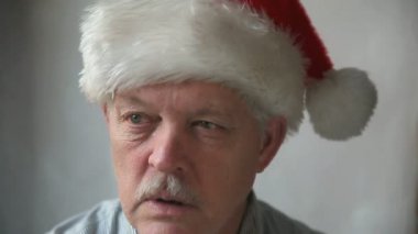 Noel Baba şapkalı yaşlı bir adam huysuz bir şekilde 