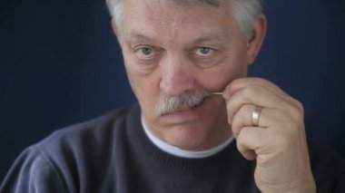 Yaşlı bir adam dişlerini kürdanla temizler..