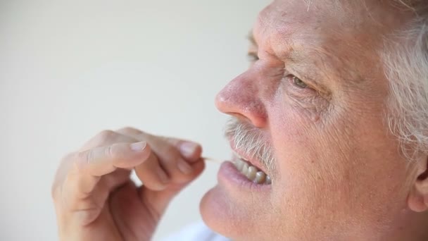 Een Senior Man Reinigt Zijn Tanden Met Een Tandenstoker — Stockvideo