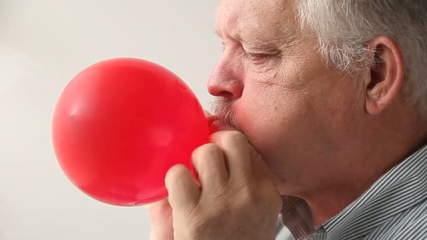 Hombre Mayor Infla Globo Rojo Ata — Vídeos de Stock