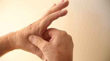 Bir adam işaret parmağı ve başparmak arasında ağrılı alan ovuşturuyor.