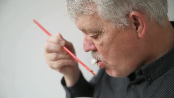 Senior Man Eet Een Stukje Garnalen Sushi Met Stokjes — Stockvideo