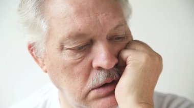 Yaşlı adam çenesini yaslar ve soruları cevaplar..