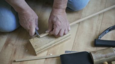 Bir adam bir tahta parçasını kesmek ve kesmek için maket bıçağı kullanır.