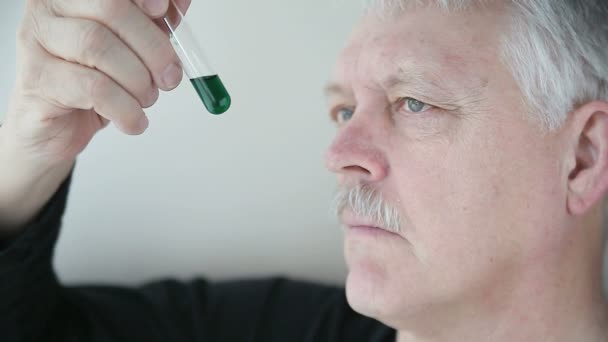 Homme Âgé Examine Liquide Vert Foncé Dans Une Éprouvette — Video