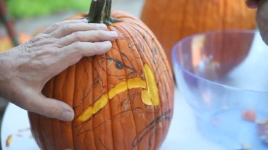 Bir adam eşsiz bir jack o'fener yüzü yontmak için onun kroki kullanır