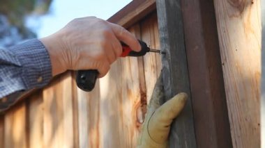 Bir çit bir vida koymak için matkap kullanarak adam closeup