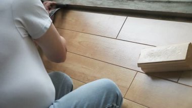 Pencereden laminat parke ler dinleyen bir adam.