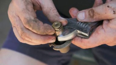 Çamurlu elleri olan bir adam arızalı bir fıskiye kafası üzerinde çalışıyor.