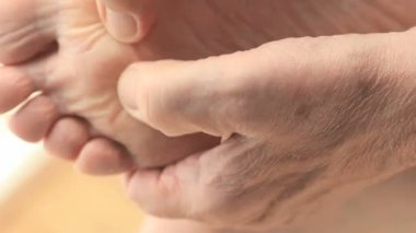 Bir adam ağrık ayağına masaj yapıyor.