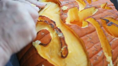 Bir adam onun Halloween balkabağı üzerinde son rötuşları koymak için keskin bir araç kullanır