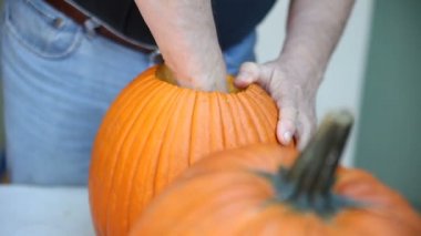 Bir adam bir balkabağı tohumları ve lifli malzeme dışarı kepçe için bir kaşık kullanır.