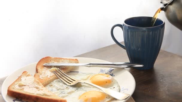 Vedle talíře smažených vajec a topinek se nalévá káva.