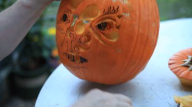 Bir adam bir jack o'fener üzerinde bir bıçak ve kavun topu aracı kullanır