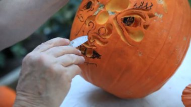 Bir balkabağı üzerinde çiziminin satırlarını takip eden bir adam