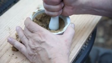 Bir adam mürekkep pigmenti olarak kullanmak için bir toz meşe safra öğütür