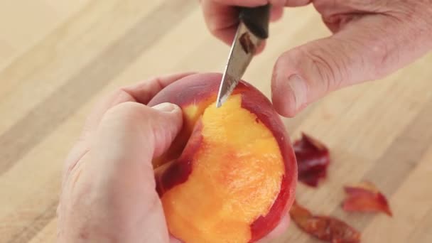 Ein Mann Entfernt Die Schale Von Einem Frischen Saftigen Pfirsich — Stockvideo