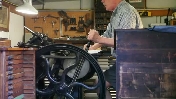 Ein Mann Druckt Seinem Atelier Karten Auf Einer Antiquitätenpresse — Stockvideo
