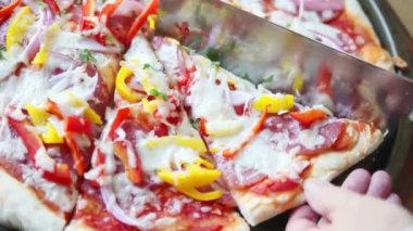 Biber ile salam pizza bir dilim kesmek için bir mutfak bıçağı kullanarak