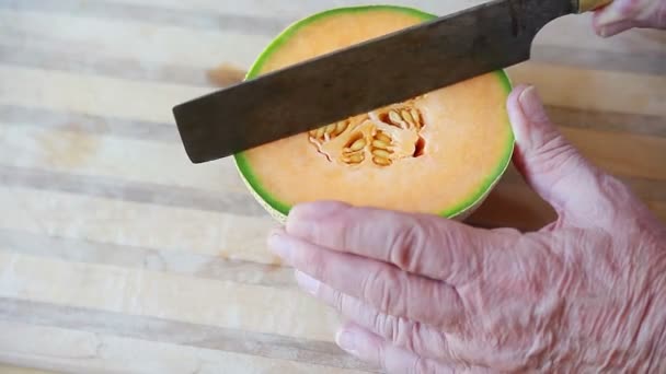 Een Man Snijdt Een Cantaloupe Een Snijplank — Stockvideo