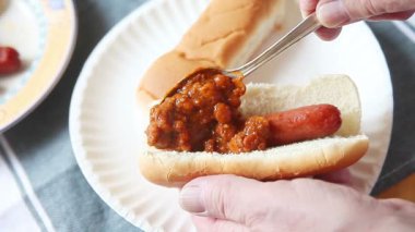 Başka bir topuz ile kağıt tabak üzerinde bir sosisli kaşıklama biber