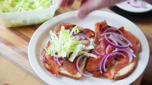 Een Man Voegt Geraspte Sla Toe Aan Een Sandwich — Stockvideo