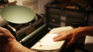 Bir yazıcı antika bir pres üzerinde kartların bir dizi üzerinde çalışır